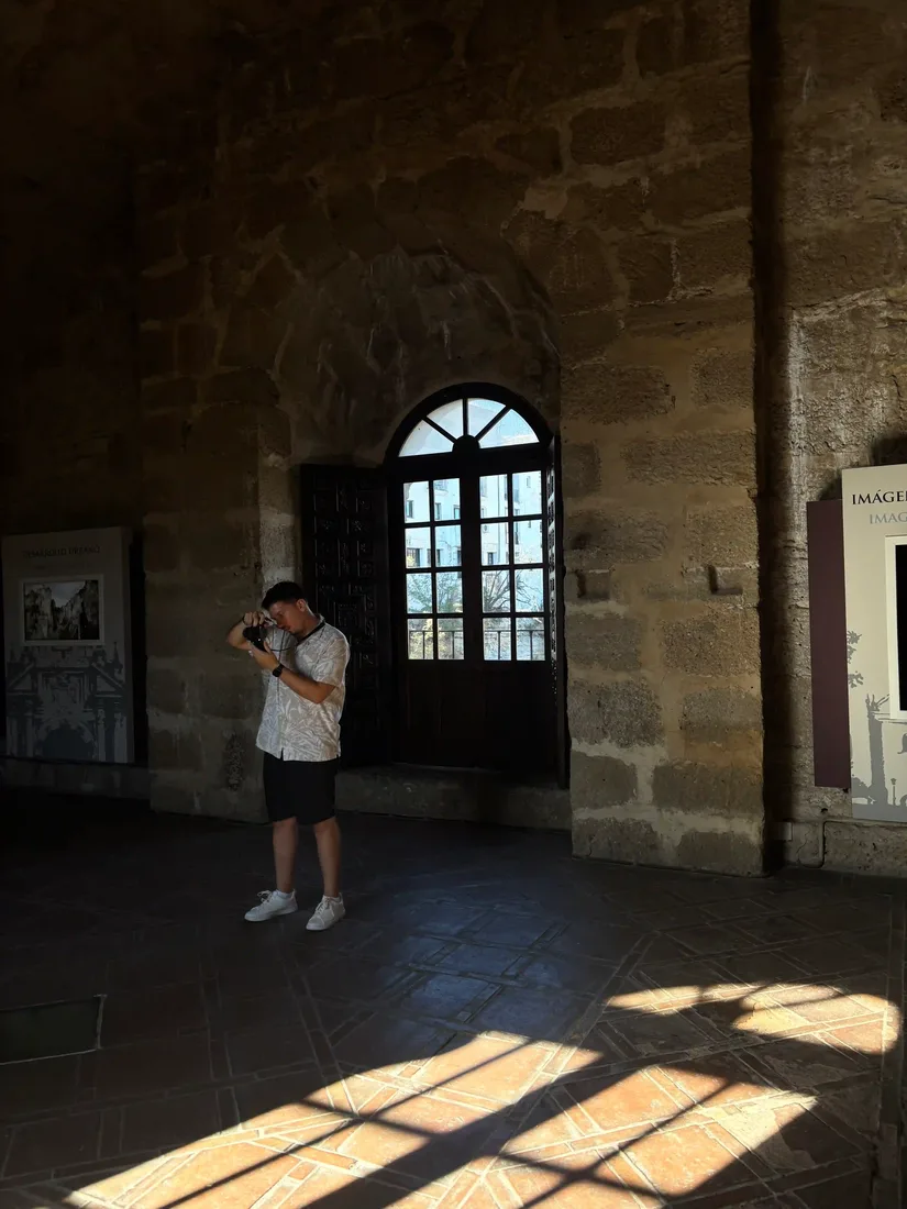 Diogo Carvalheiro a fotografar dentro de um edifício histórico, com a luz a entrar pela janela